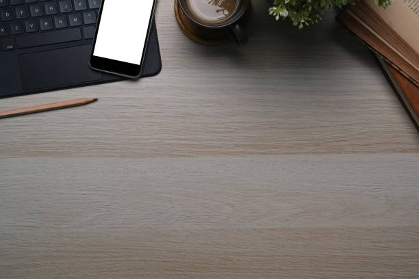 istock Top view of comfortable workplace wit smart phone, wireless keyboard, notebook, coffee cup ad copy space on wooden table. 1302380283