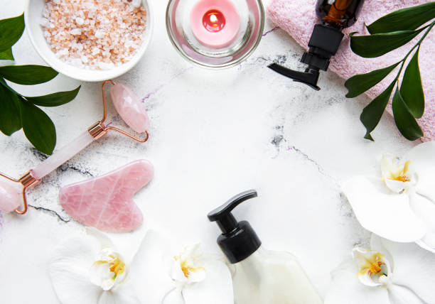 istock Face massage jade roller with cosmetic product on white marble background 1302382429