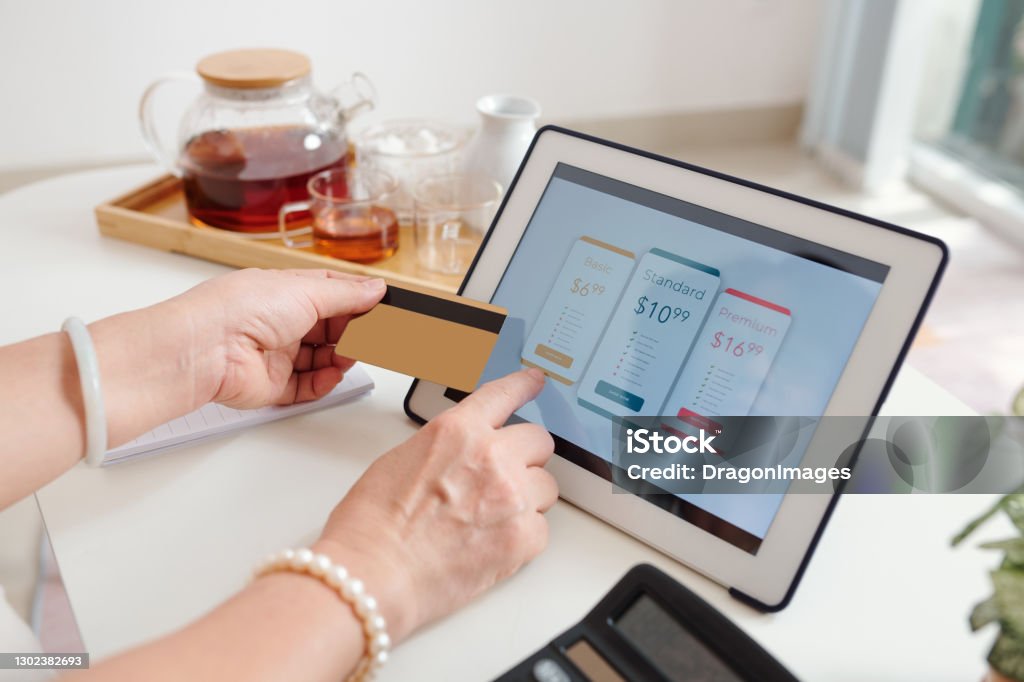Woman choosing subscription plan Hands of senior woman choosing subscription or payment plan on tablet computer and paying with credit card Subscription Stock Photo
