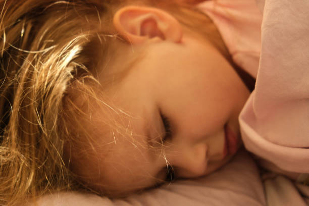 istock Soft blurred image sleeping little girl in pjamas  lie down on bed 1302383360