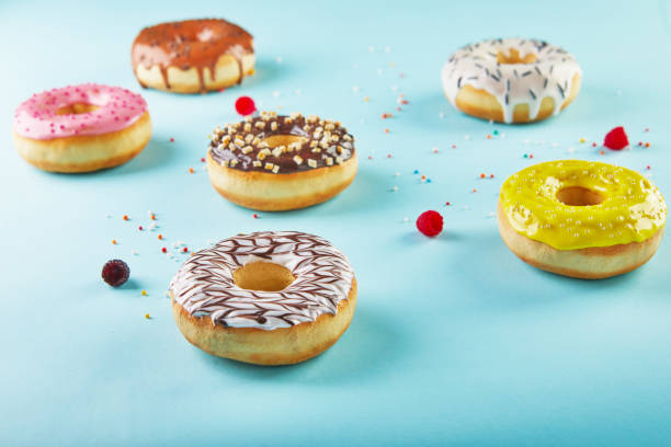 istock Multicolored donuts with frosting and sprinkles on blue background 1302384567