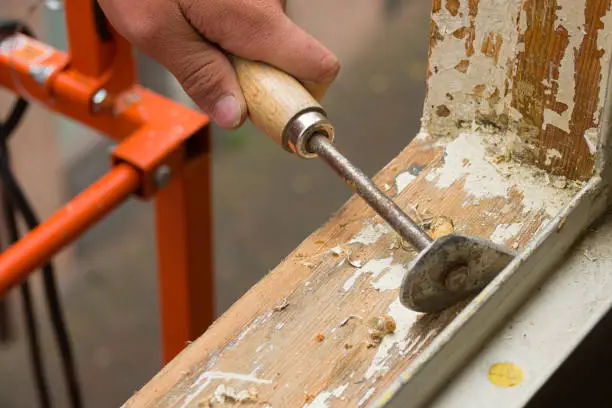 Photo of House renovation. A painter removing old paint with a scraper.