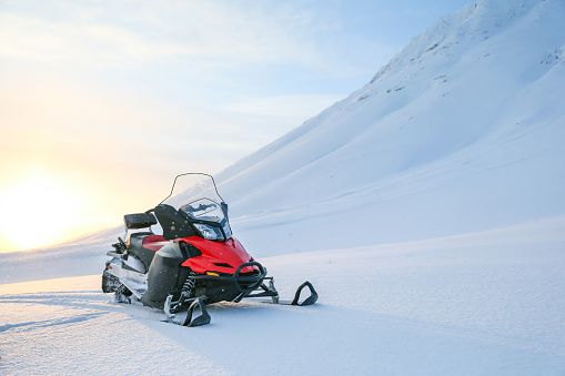 red snowmobile on a background of snowy mountains on a sunny day.