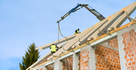 Construction workers working on roof top of new house.