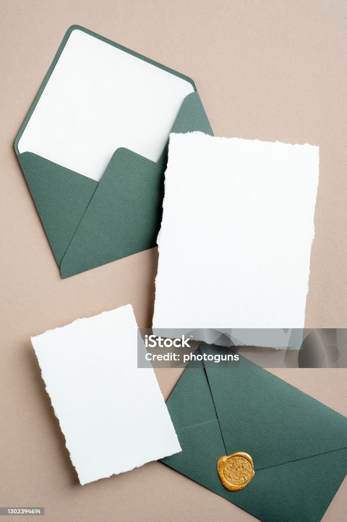 Elegant wedding invitation cards mockups and green envelopes on brown background. Flat lay, top view, copy space. Wedding Invitation Stock Photo