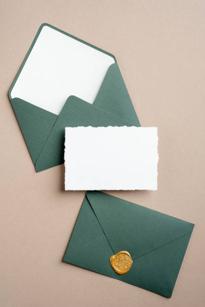 istock Wedding invitation card mockup and green envelopes on brown background. Flat lay, top view, copy space. 1302394619