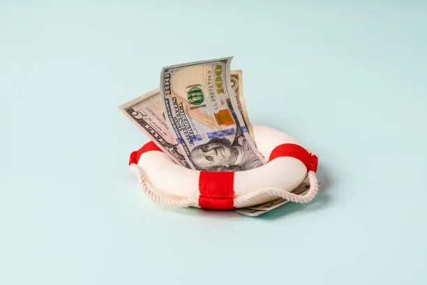 A lifebuoy with banknotes lie on a blue background, the concept of assistance and security in finance