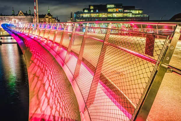 Lille Langebro is a modern cycle and pedestrian bridge in Copenhagen, Denmark. Elegant and contemporary overpass across the city 's canal or quayside coloured by pink and fuchsia lights at night