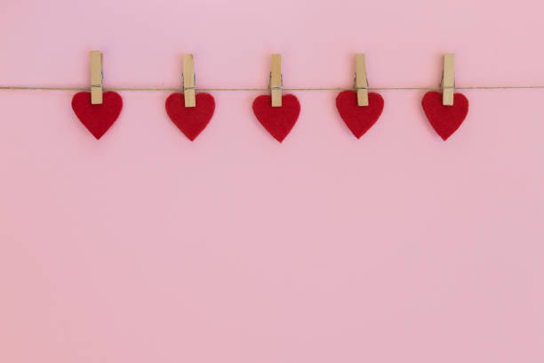 istock Red hearts hanging on the clothesline on pink background. 1302400754