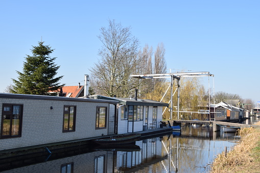 dutch houseboats on a water with beautiful reflections of a drawbridge near Roelofarendsveen.