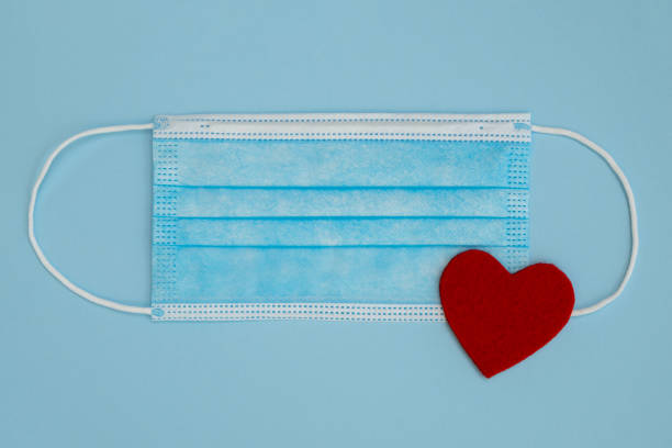 istock Medical mask on a blue background with red heart. 1302401628