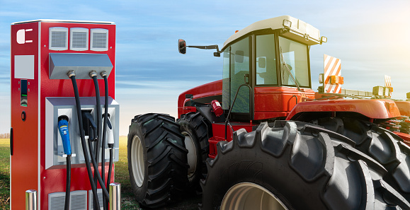 Electric vehicles charging station on a background of agricultural tractor. Concept