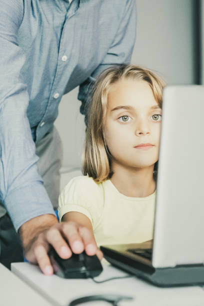 istock Middle-aged teacher checking task and standing behind girl 1302404407