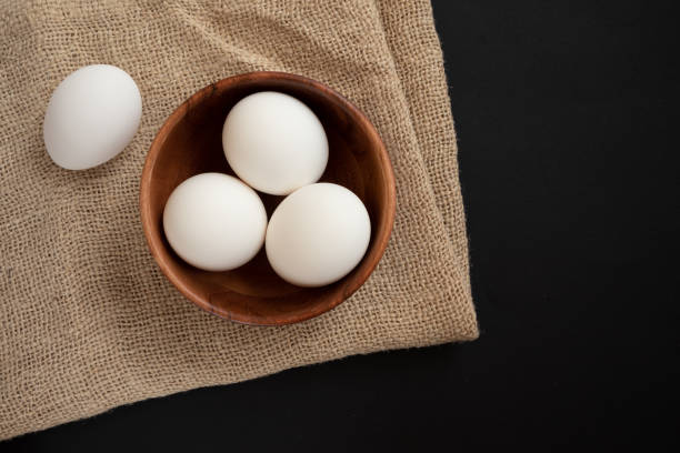 istock Raw chicken eggs in a wooden plate on the table. 1302404446