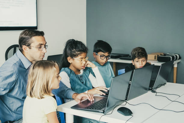istock Multiethnic pupils doing task with help of teacher 1302404640