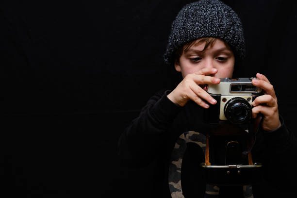 istock Five-year-old boy in a wool cap taking photos and selfies with an old analog camera 1302405729