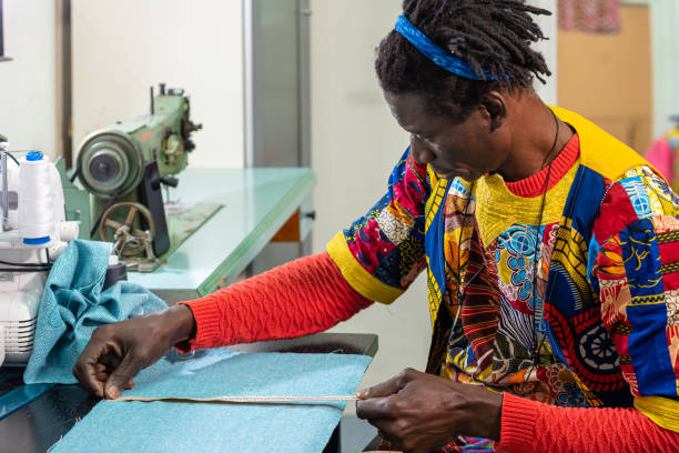 istock african tailor dressed in traditional clothes and fabrics at work in his workshop, production of unique clothes with modern style and colors of africa, small business, business concept of craftsman 1302409713