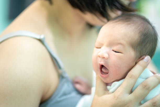 la mère tenait le bébé roter, en utilisant ses mains pour soutenir le menton. - baby yawning asian ethnicity newborn photos et images de collection