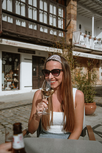 A young woman drinking a glass of white wine outdoors