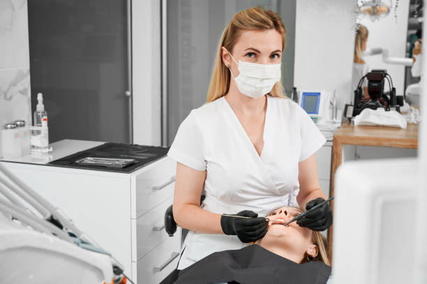 female dentist at work with patient examining her teeth with dental tools - ambulant patient imagens e fotografias de stock