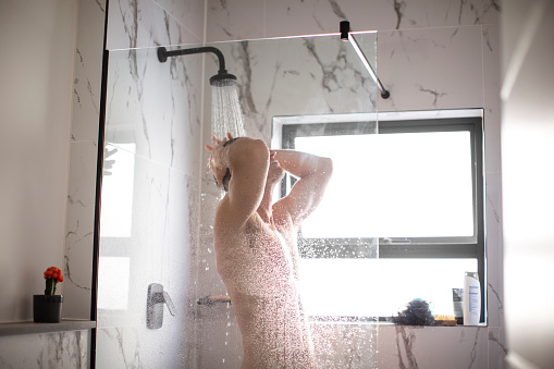 A caucasian adult male taking a shower at his apartment in Cape Town, South Africa.
