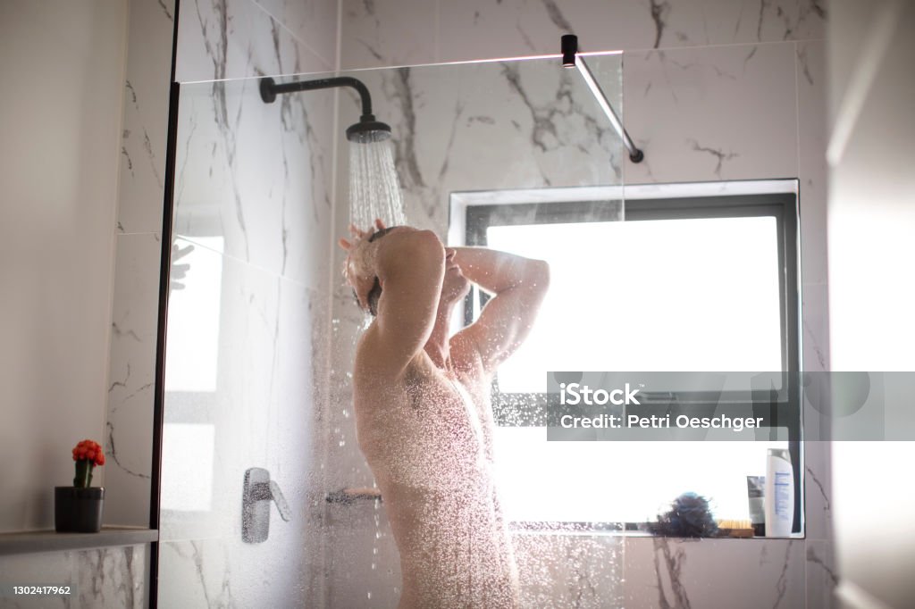 A caucasian adult male taking a shower at home. A caucasian adult male taking a shower at his apartment in Cape Town, South Africa. Shower Stock Photo