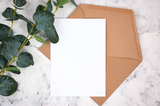 istock Blank white card, envelope and eucalyptus branch on white marble background. Blank invitation. Flat lay. 1302418044