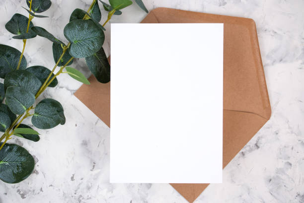 istock Blank white card, envelope and eucalyptus branch on white marble background. Blank invitation. Flat lay. 1302418050