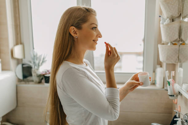 istock Young woman takes medicine from plastic container 1302418171