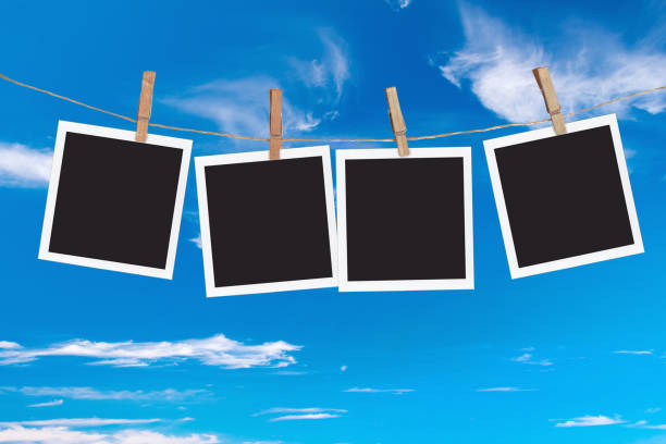 istock Four blank instant photo frames hanging on a rope, on blue sky background 1302418407