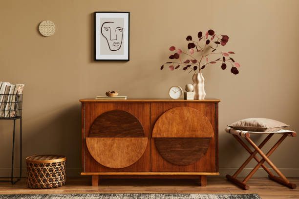 istock Stylish interior with design wooden commode, stool, dried flowers in vase, unique decoration, carpet, mock up poster frame and elegant personal accessories. Modern living room in classic house. 1302419078