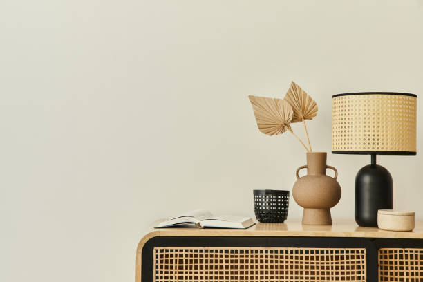 istock Modern scandinavian home interior with design wooden commode, dried leaf in vase, books, table lamp and personal accessories in stylish home decor. Template. Copy space. White walls. 1302419121