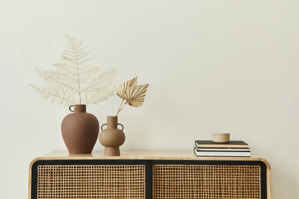 istock Modern scandinavian home interior with design wooden commode, dried leafs in ceramic vases and personal accessories in stylish home decor. Template. Copy space. White walls. 1302419262