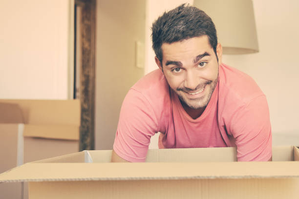istock Cheerful young man unpacking things in his new apartment 1302419312
