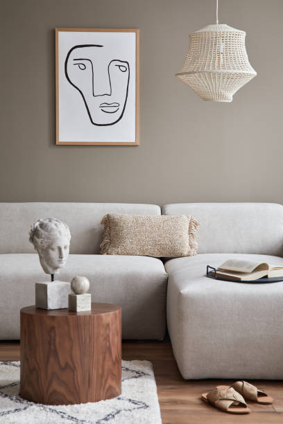 istock Stylish interior with design neutral modular sofa, mock up poster frames, coffee tables, wooden tray, book, decoration, slippers and elegant personal accessories in modern home decor. Template. 1302419549