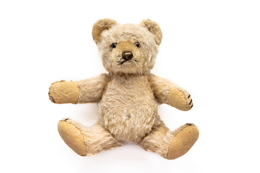 cute sitting teddy bear, children's toy, very old and worn, used. On a white background.