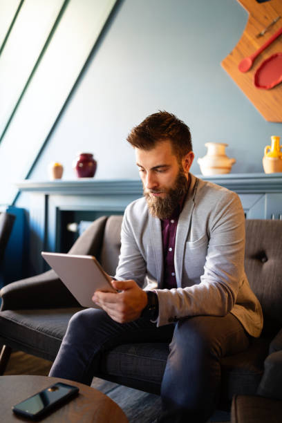 istock Young business man working, relaxing on the sofa with a tablet 1302423116