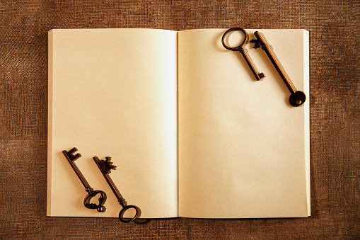 Old key lying on blank book on textile background