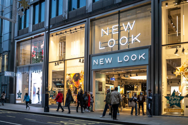 New Look clothes modern city centre store shop with brand logo and sign illuminated at night London, UK - October 29 2020 New Look clothes modern city centre store shop with brand logo and sign illuminated at night busy with tourists and shoppers high street shops stock pictures, royalty-free photos & images