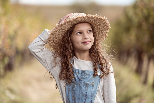 Portrait of happy smiling little girl child wearing summer straw hat in sunny day