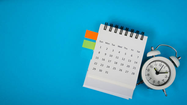 istock white analog alarm clock on white calendar with grunge blue background with copy space, business meeting schedule, travel planning or project milestone and reminder  concept 1302428818