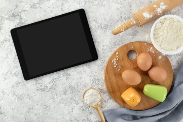 istock Ingredients and tools for baking and tablet with blank screen and place for text or image on white table. recipe, cookbook, cooking courses online template 1302429186