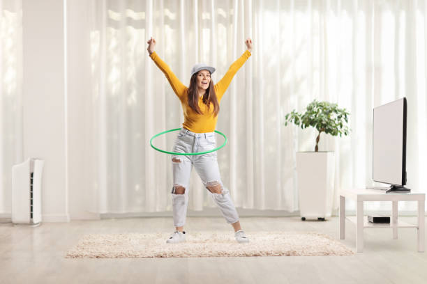 joven girando un hula hoop en casa en una sala de estar - hooping fotografías e imágenes de stock