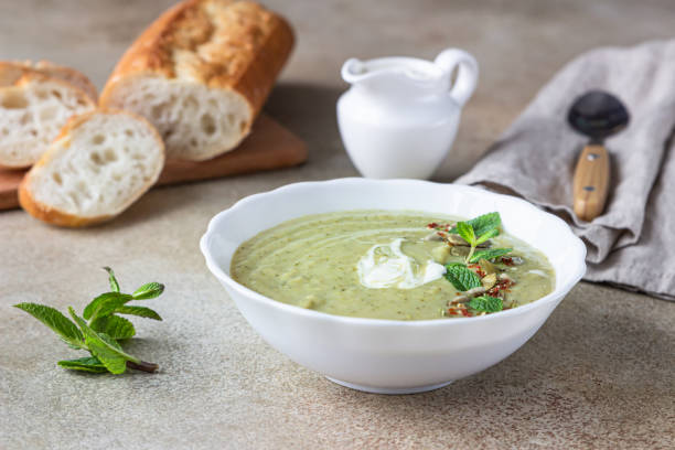 istock Broccoli cream soup served with mint, cream, seeds and fresh bread on concrete background. Healthy vegetarian food concept. 1302433557