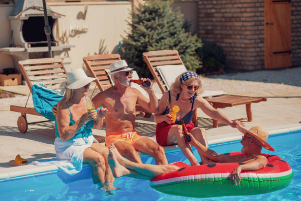 istock Senior people drinking cocktails and relaxing by the pool 1302435871
