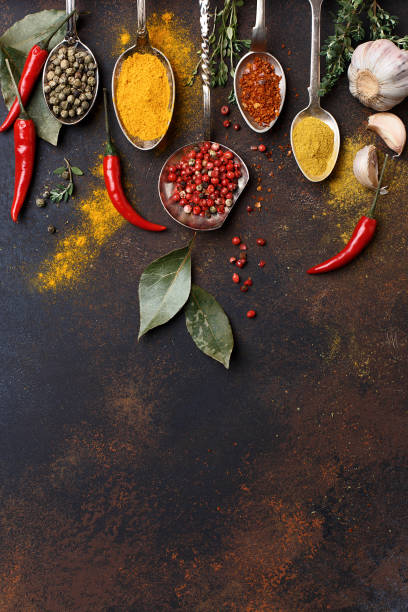 condimento multicolore assortito in cucchiai d'argento su sfondo marrone - spice ayurveda herb curry powder foto e immagini stock
