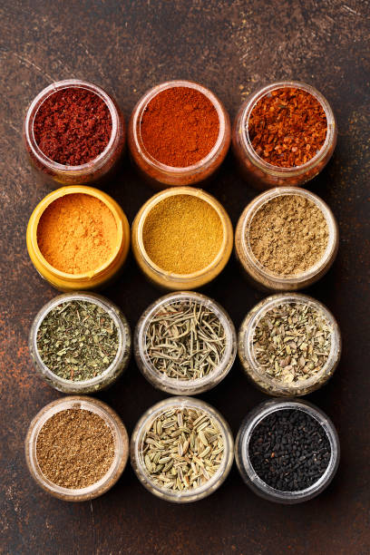 Assorted multicolored condiment in jars on brown background Set of various colorful spices in jars over dark brown concrete background. Top view, close up, flat lay. Food background, ingredients for cooking sumac spice stock pictures, royalty-free photos & images