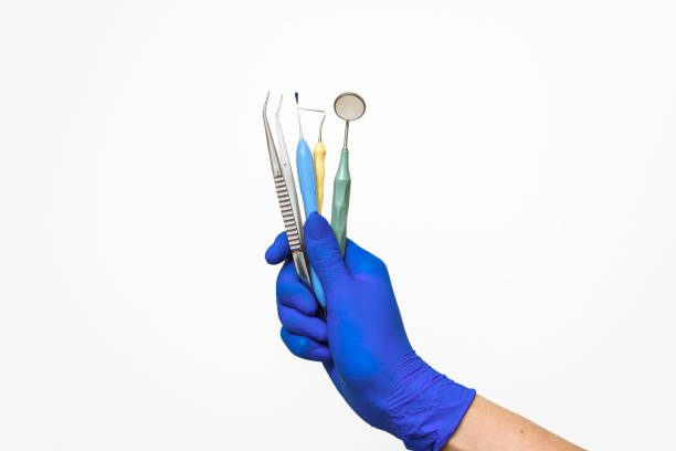 la main du dentiste dans un gant bleu tient des instruments dentaires. publicité de la dentisterie et des services dentaires - dentist mirror orthodontist carver photos et images de collection