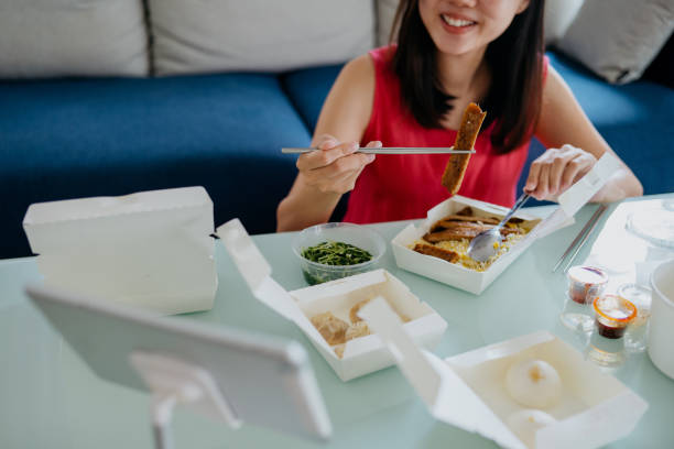 istock Young asian woman video calling while having take away food 1302437829