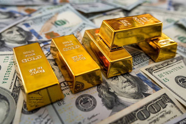 istock Gold bullion on pile us dollar bills as background 1302437838